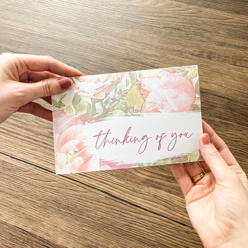 hands holding floral card that says thinking of you